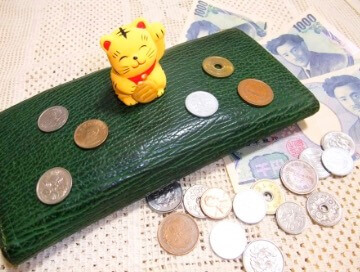 財布と金運アップの招き猫と札と小銭の画像